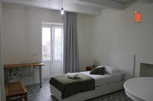 a bedroom with a bed and a desk and a window at La Casetta nel Borgo in Cerisano