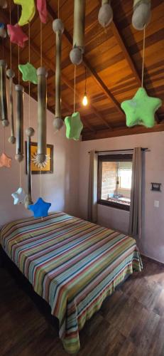 a bedroom with a bed with colorful sheets and lights at CHALEZINHO Da LÚ in Carrancas