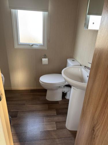 a bathroom with a toilet and a sink and a window at Steph's Haven in Skipsea