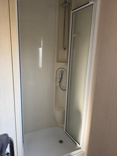 a bathroom with a shower with a mirror and a toilet at Steph's Haven in Skipsea