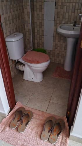 a bathroom with a toilet and a pair of slippers at Budget bliss4 bnb Ruaka in Ruaka