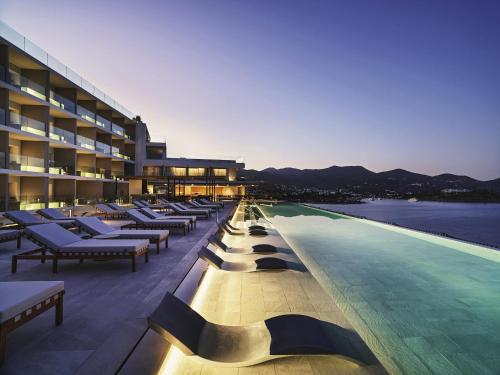 a hotel with a swimming pool with lounge chairs at NIKO Seaside Resort MGallery in Agios Nikolaos
