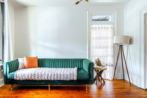 a living room with a green couch with an orange pillow at Prime Location Top Rated Clean Parking Free! in Columbus