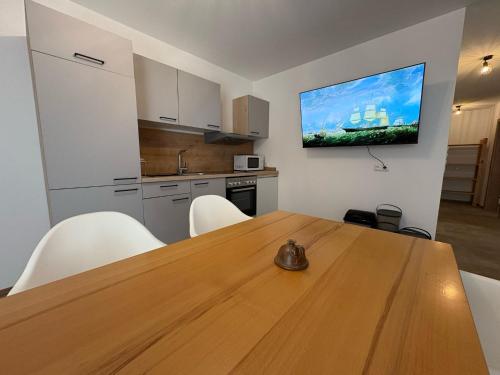 a kitchen with a wooden table and a television on a wall at Danner Appartements Wolfsegg am Hausruck- Ferienwohnung & Business-Appartements Ruhige Lage, moderne Ausstattung, faire Preise in Wolfsegg am Hausruck