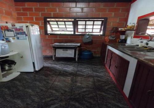 a kitchen with a white refrigerator and a table at Casa Condado Maricá in Maricá