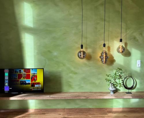 a living room with a tv and three pendant lights at Nordic Zen Loft mit Garten in Magdeburg