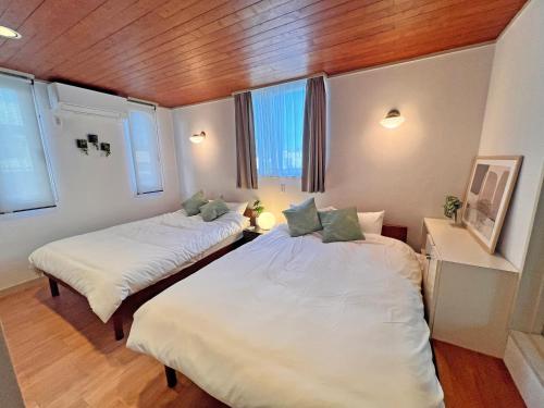 two beds in a room with wood floors and windows at Jomo Stay Takasaki 2 -the Garden- in Takasaki