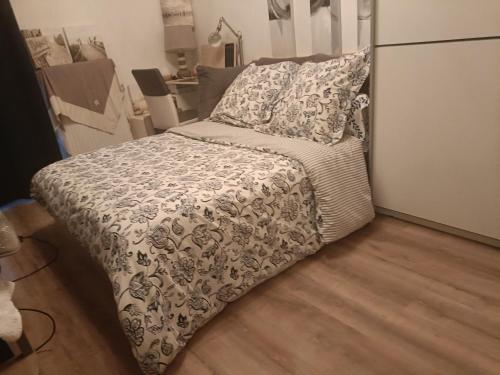 a bed with a black and white comforter and pillows at Chambre d hôte chez l habitant in Meyzieu
