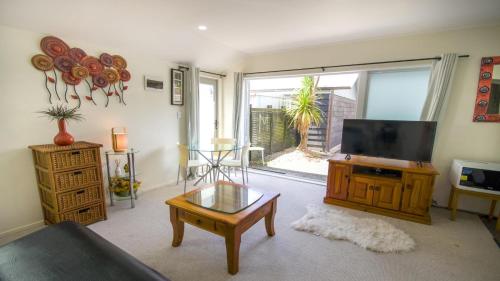 a living room with a television and a coffee table at Beautiful and Bright Studio Apartment Botany Downs in Auckland