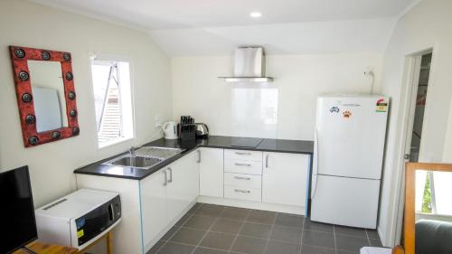 a kitchen with a white refrigerator and a sink at Beautiful and Bright Studio Apartment Botany Downs in Auckland