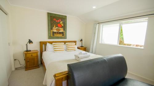 a bedroom with a bed with a chair and a window at Beautiful and Bright Studio Apartment Botany Downs in Auckland