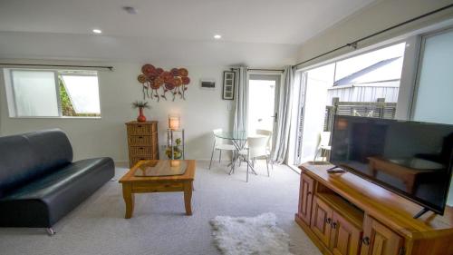 a living room with a couch and a flat screen tv at Beautiful and Bright Studio Apartment Botany Downs in Auckland