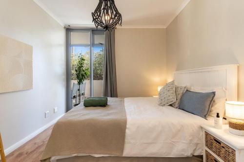 a bedroom with a large bed and a window at Melrose Tide 1 Bed Spacious Apartment in Muizenberg