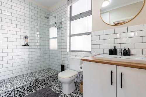 a bathroom with a toilet and a sink and a mirror at Melrose Tide 1 Bed Spacious Apartment in Muizenberg