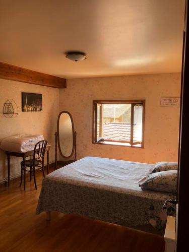 a bedroom with a bed and a table and a mirror at Gîte de la Croix Mandet in Vensat