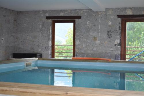 a large swimming pool with two windows in a room at Chambre suite de L'argentier in Noyarey