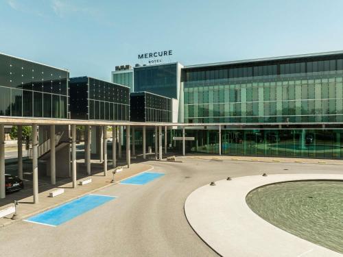 a large glass building with a pool in front of it at Mercure Tallinn in Tallinn