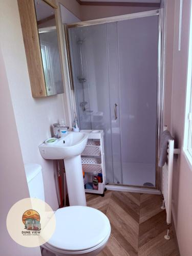 a bathroom with a shower and a sink and a toilet at Dune View Caravan in Ynys-lâs Station
