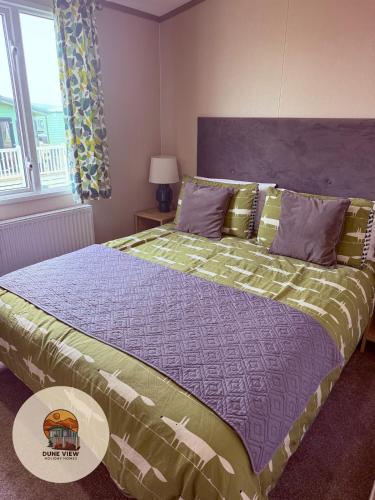 a bedroom with a bed with a purple and green comforter at Dune View Caravan in Ynys-lâs Station