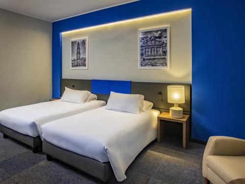 Dos camas en una habitación con una pared azul. en Mercure Hotel President Lecce, en Lecce