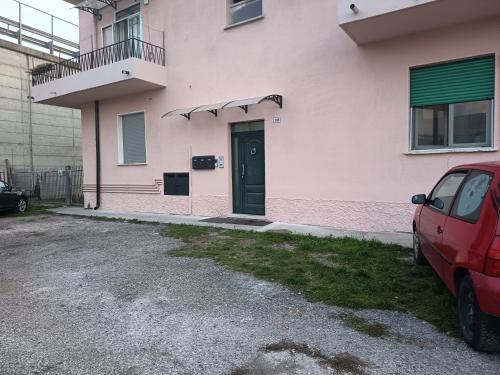 a pink house with a door and a car parked in front at 2 passi dalla fiera SOGNI D'ORO in Verona