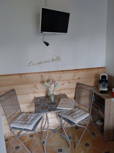 a table with two chairs and a television on a wall at Mon petit coin de paradis in Coursan