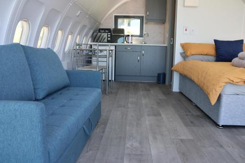 a living room with two blue couches and a kitchen at AeroHeaven Glamping in Cavan