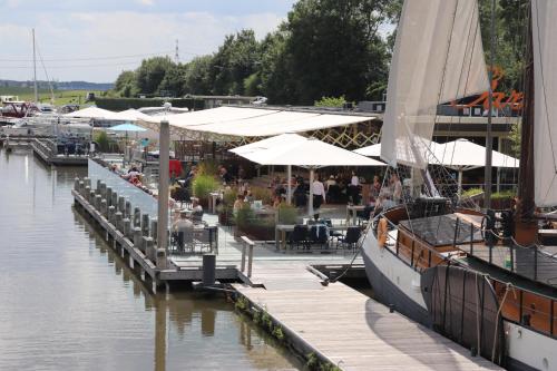 een zeilboot aangemeerd aan een kade met een restaurant bij Tiny Boat House #4 in Garnwerd