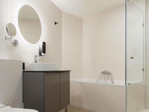 une salle de bain avec un lavabo, une baignoire et un miroir dans l'établissement Aparthotel Adagio Malta Central, à Msida