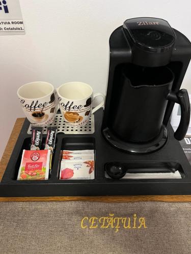 a black coffee maker and two cups on a tray at Cetățuia - Ultra-Central Râșnov Stay - Parking and Nature Close to Bran, Dino Parc and More in Râşnov