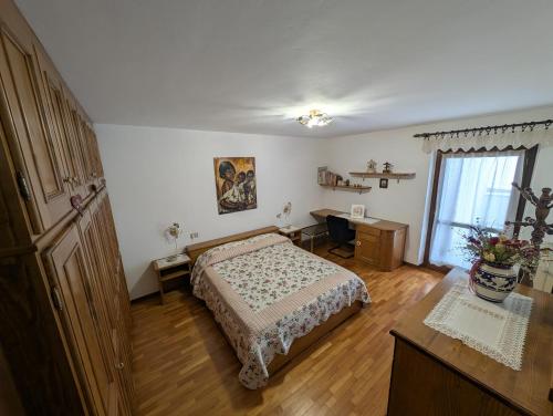 a bedroom with a bed and a desk and a window at Appartamento Nonna Marcella in Santo Stefano di Cadore