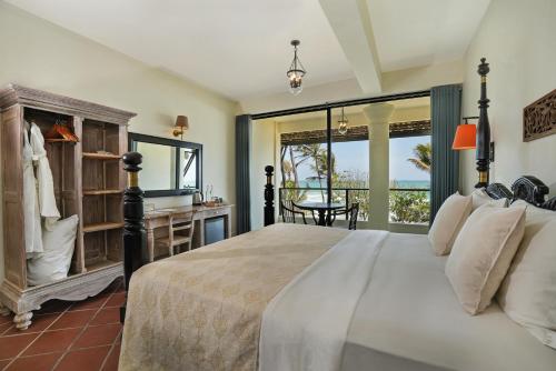 Un dormitorio con una cama y un escritorio y una ventana. en Naomi Beach Resort - Adults only, en Weligama