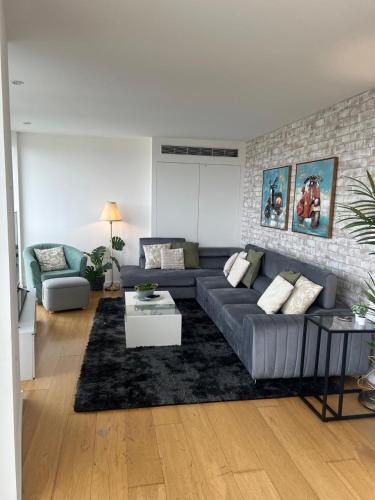 ロンドンにある62 Sqm High Rise Apartment Canary Wharfの青いソファとレンガの壁が備わるリビングルーム