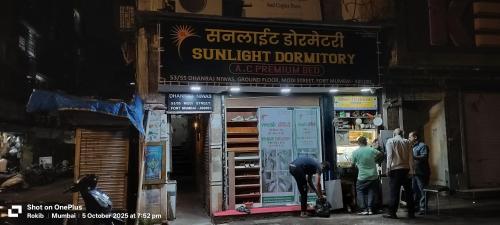 a group of people standing outside of a sunlitinionury shop at Sunlight Dormitory in Mumbai