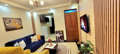 a living room with a blue couch and a wooden wall at GoldenSpark Homes in Thika