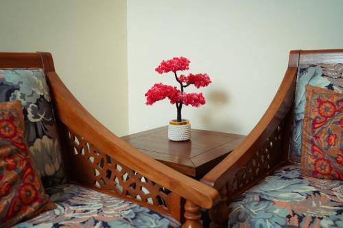 a table with two red flowers in a vase on it at Luxury cozy studio apartment with balcony in Lahore