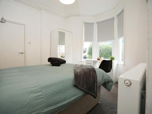 a bedroom with a large green bed with windows at Spacious 4 Bedroom House - Sleeps 8 Guests, Contractors, Groups, Families, Business, Leisure & Relocation Stays Welcome, 13 Minutes From City Centre, Fast Wi-Fi, Smart TV In Lounge & FREE Parking, Long Stays And Short Stays Welcome in Bristol