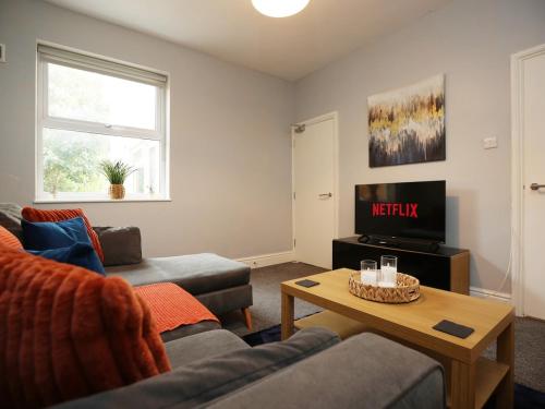 a living room with a couch and a tv at Spacious 4 Bedroom House - Sleeps 8 Guests, Contractors, Groups, Families, Business, Leisure & Relocation Stays Welcome, 13 Minutes From City Centre, Fast Wi-Fi, Smart TV In Lounge & FREE Parking, Long Stays And Short Stays Welcome in Bristol