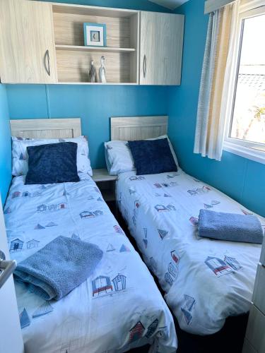 two beds in a room with blue walls at Newquay Bay Resort - Sea Breeze 61 in Newquay