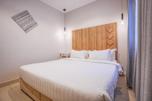 a bedroom with a large white bed with a wooden headboard at Mabaat-White Pearl Compound 600 C Villa 24 in Jeddah