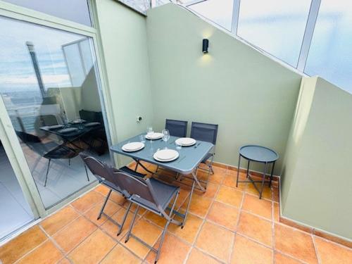 a dining table and chairs in a room with windows at First-Line Las Canteras Beach in Las Palmas de Gran Canaria