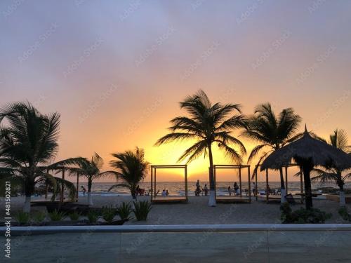 a sunset at the beach with palm trees and swings at Casa Zoe - Habitación Económica en Casa Familiar in Guayabal