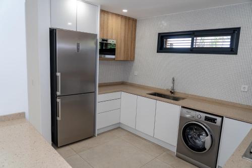 a kitchen with a refrigerator and a washing machine at o som das ondas in Praia