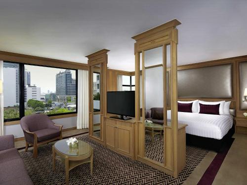 una habitación de hotel con una cama y un televisor en Grand Mercure Bangkok Atrium, en Bangkok