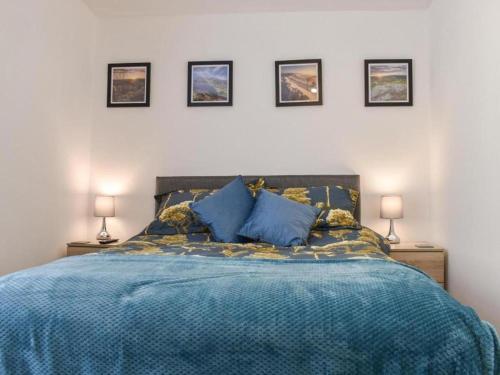 a bedroom with a blue bed with four pictures on the wall at Ladybower Apartment Central Glossop in Glossop