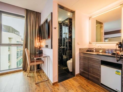 a bathroom with a sink and a shower at Mercure Singapore Tyrwhitt in Singapore