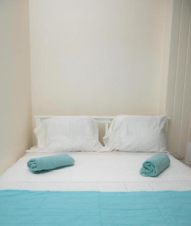 a white bed with two blue pillows on it at Gosier séjour in Le Gosier