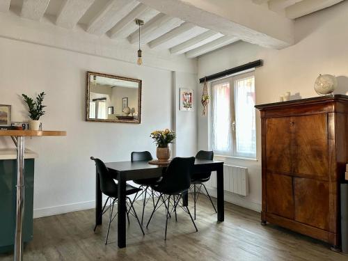 a dining room with a table and chairs and a mirror at Charmant appartement au coeur du centre-ville in Dives-sur-Mer