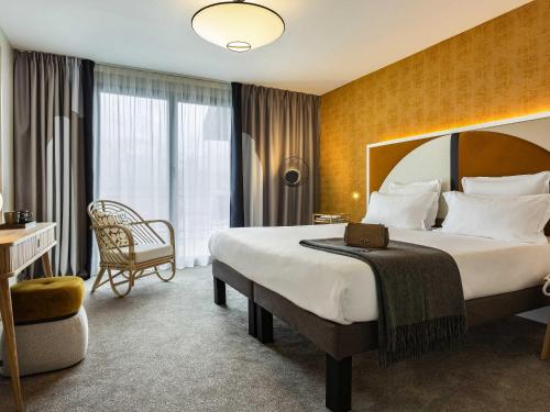 a hotel room with a large bed and a chair at Le Saint Gervais Hotel & Spa Handwritten Collection in Saint-Gervais-les-Bains