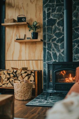 a living room with a fireplace with a stove at Inima Pustei Cabin in Măguri